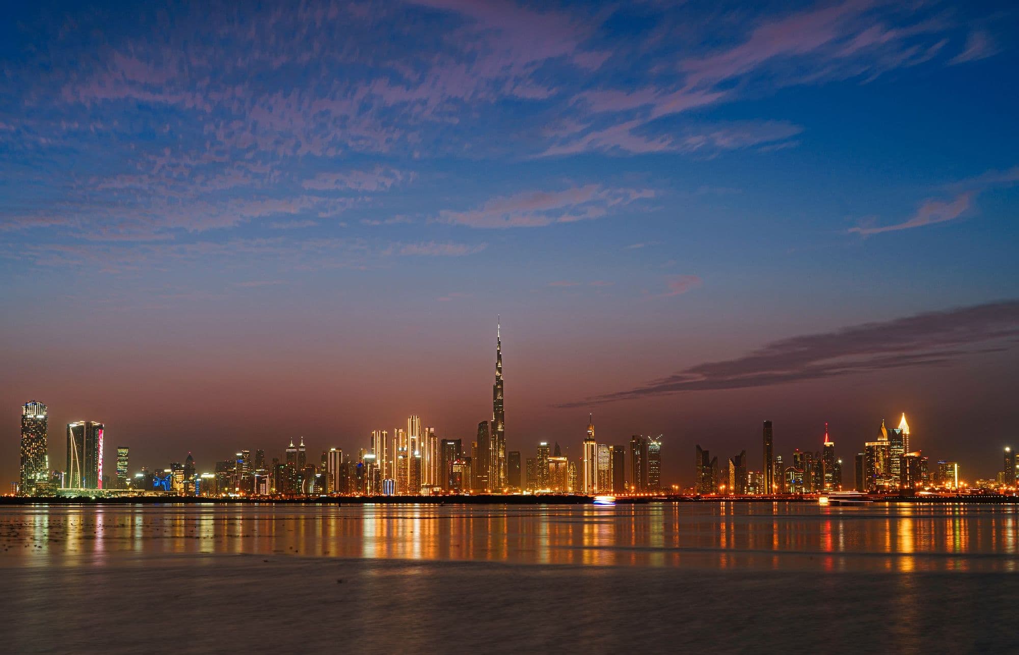 The Dubai skyline across the water at dusk.