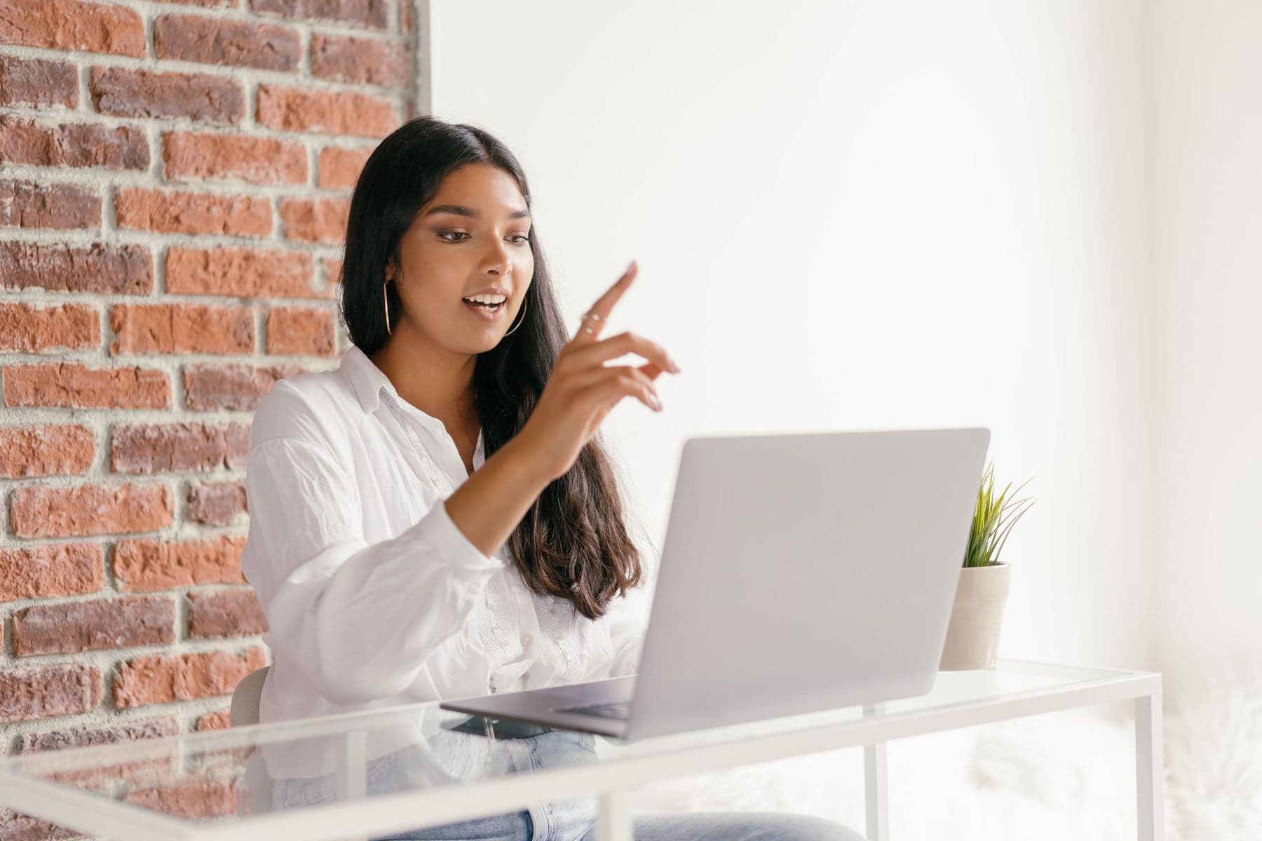 A woman talking on a video call from a bright home office.